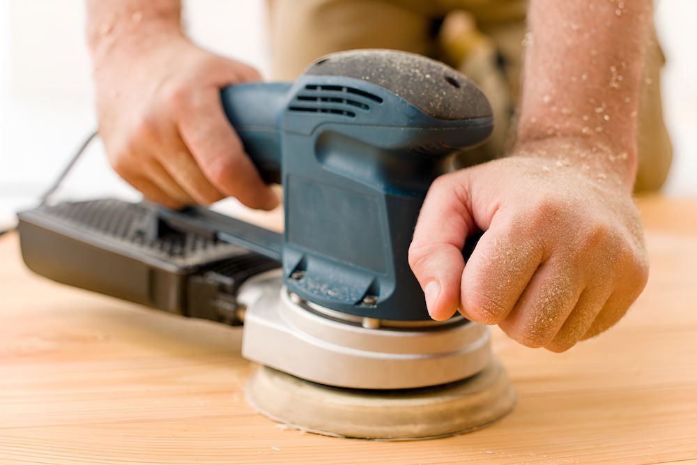 A Person Is Sanding A Piece Of Wood With A Sander — European Floor Sanding In Mount Louisa, QLD