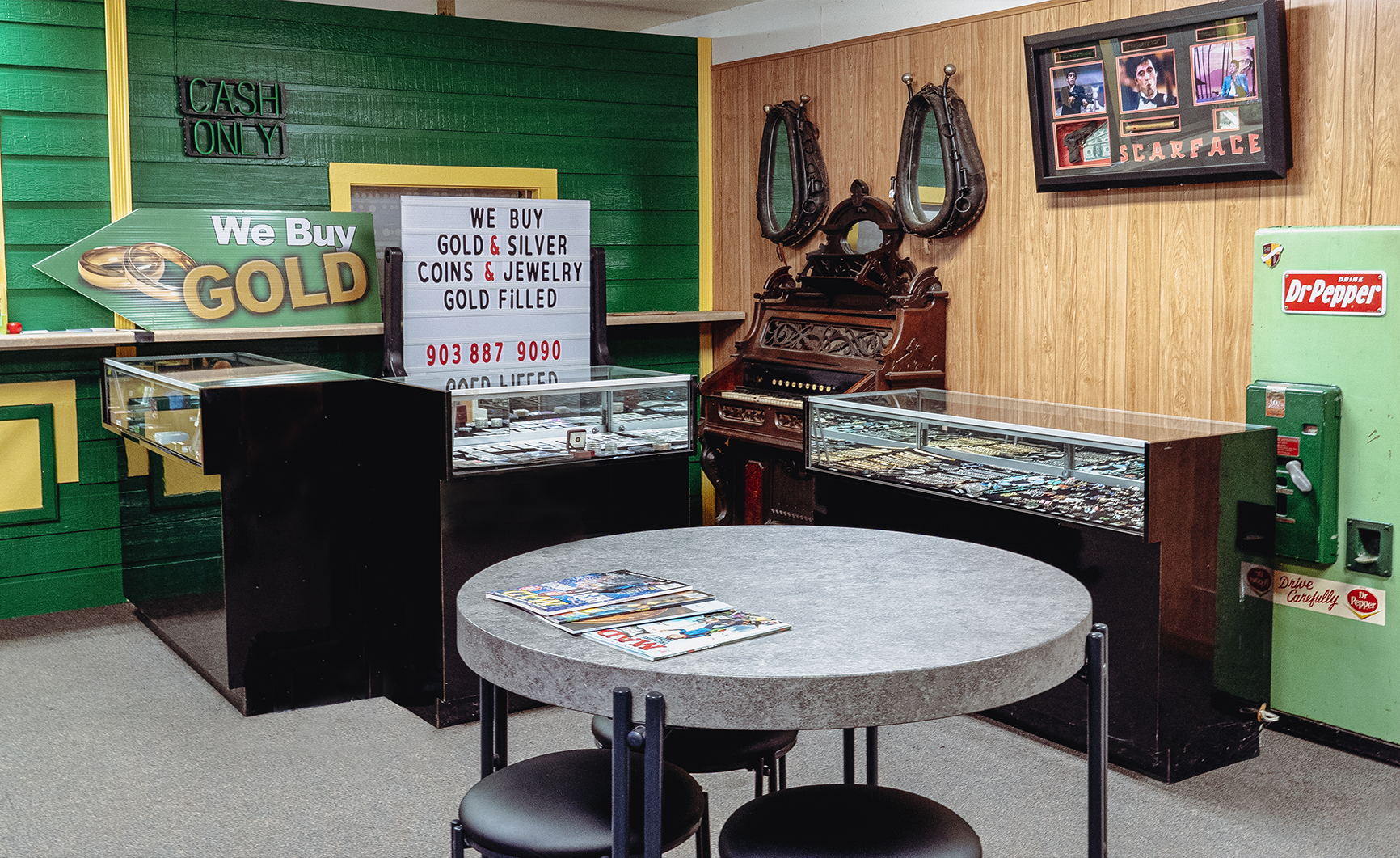 Interior shot of a store with display cases, a round table, and a green and yellow color scheme.