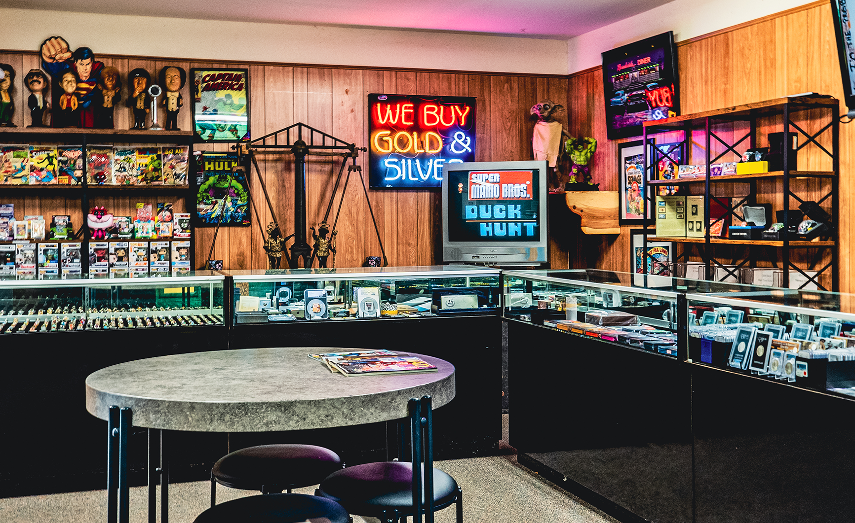 store interior with display cases, neon sign, and a round table.