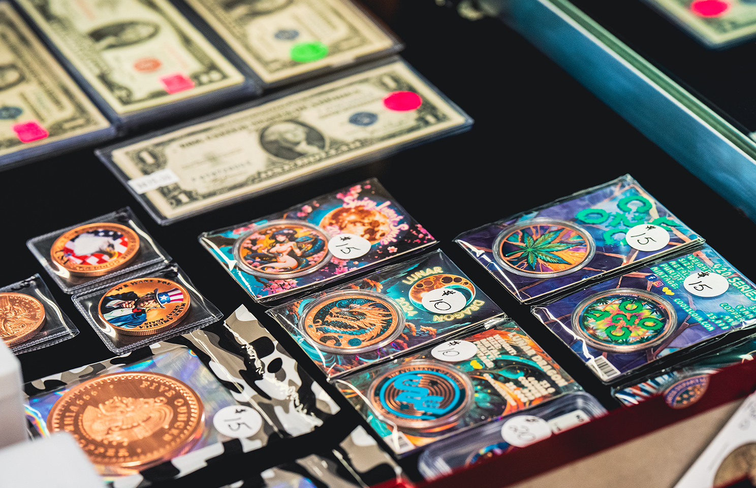 Display of coins and dollar bills for sale at a market; coins in colorful packaging.