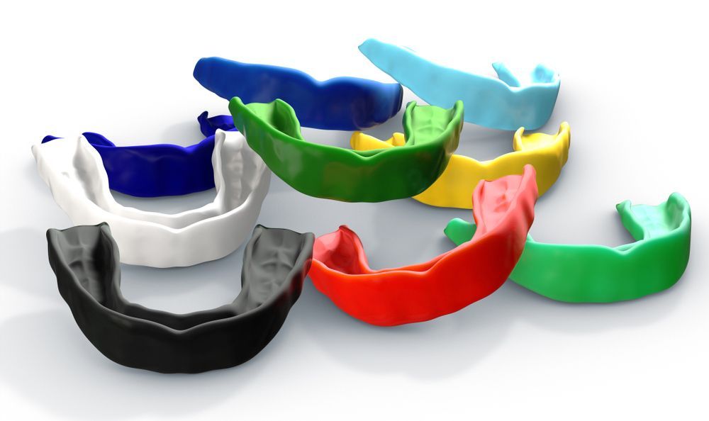 A Group Of Mouth Guards Of Different Colors Are Sitting On A Table — Mouthguards in Central Coast, NSW