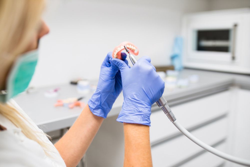 A Dentist Is Working On A Model Of A Person's Teeth In A Dental Office — Denture Remodelling in Central Coast, NSW