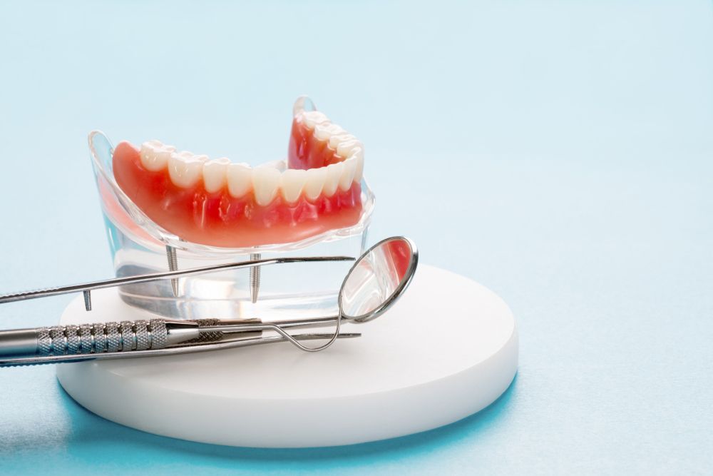 A Model Of A Denture With Dental Instruments On A Blue Background — Denture Reline in Central Coast, NSW