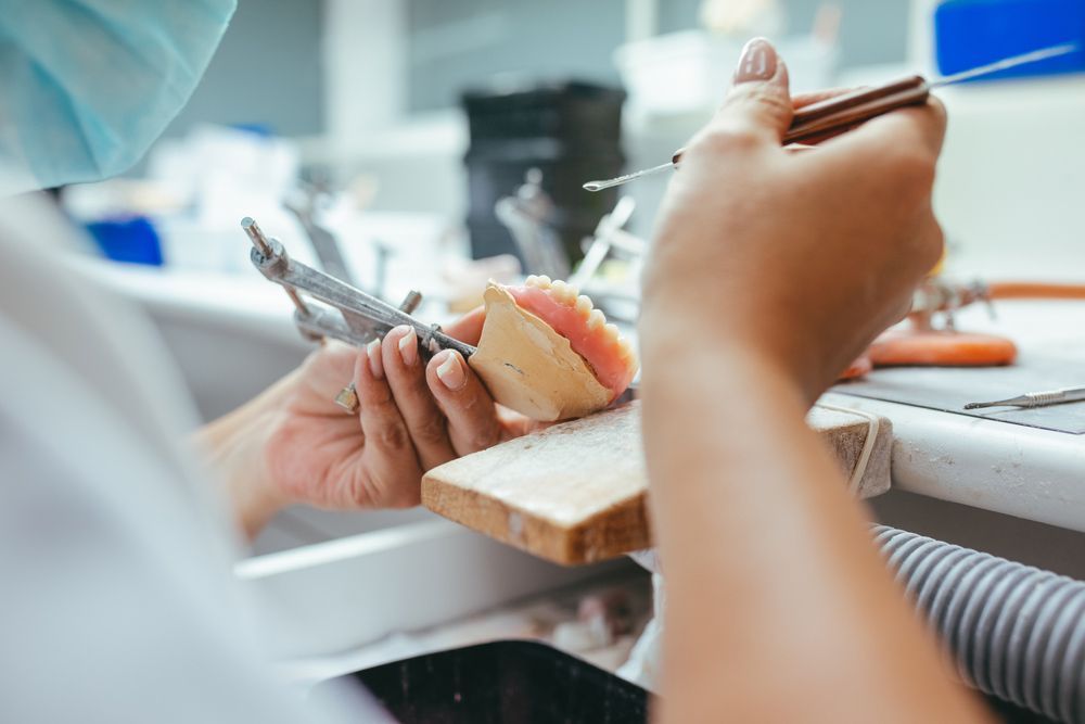 A Dentist Is Working On A Denture In A Dental Lab — Denture Remodelling in Central Coast, NSW