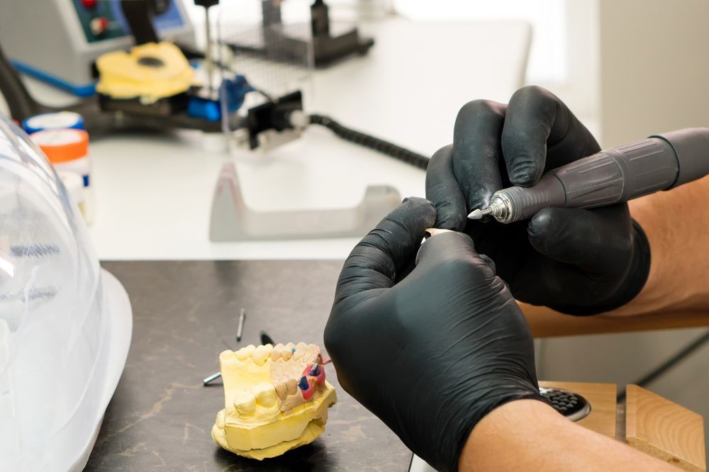 A Person Wearing Black Gloves Is Working On A Denture Model — Dentures in Port Macquarie, NSW