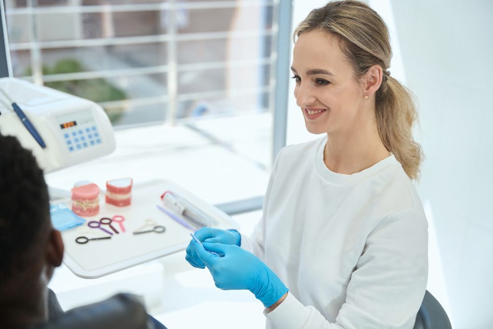 A Female Dentist Is Talking To A Patient In A Dental Office — Denture Adjustments in Central Coast, NSW