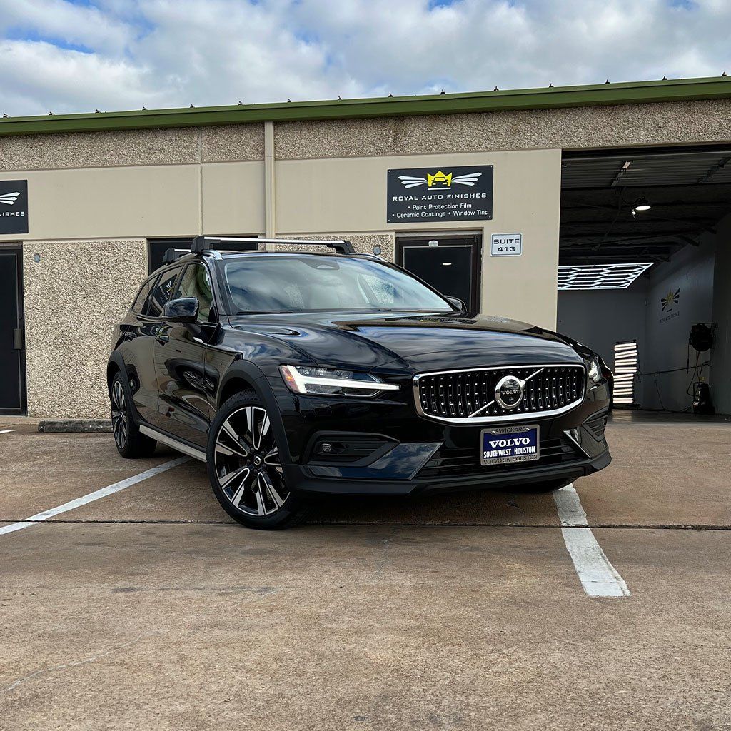 Black Volvo SUV parked in front of a building with a business sign.