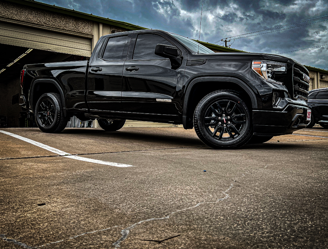 a black truck is parked in a parking lot in front of a building .