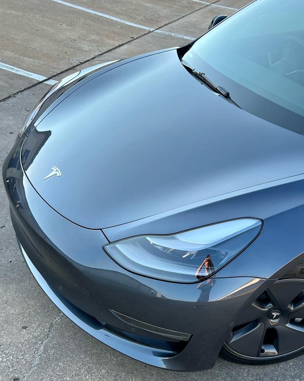 Gray BMW SUV parked on a sunny day in front of a building with black wheels and tinted windows.