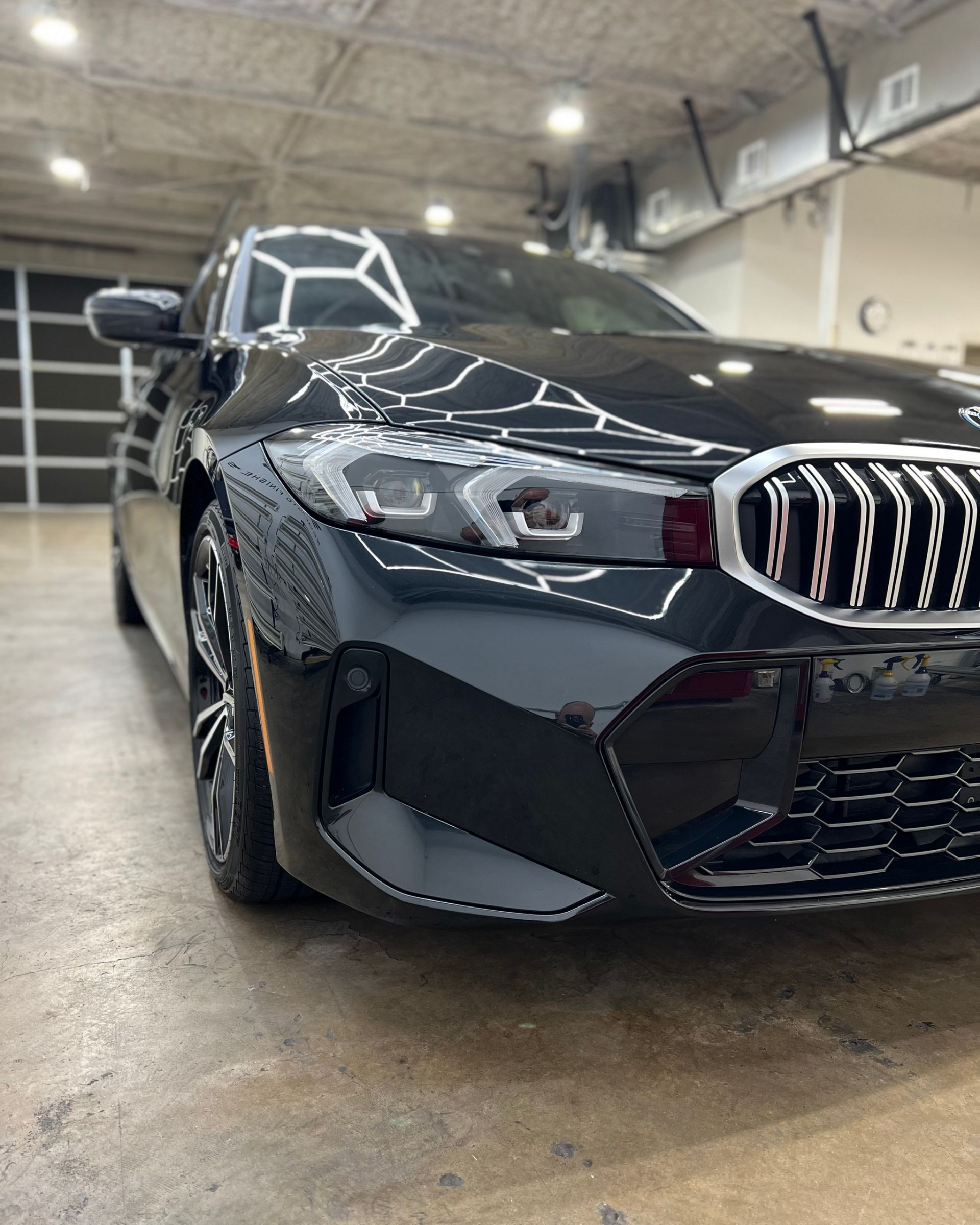 Black BMW sedan parked inside a garage, angled view of front.