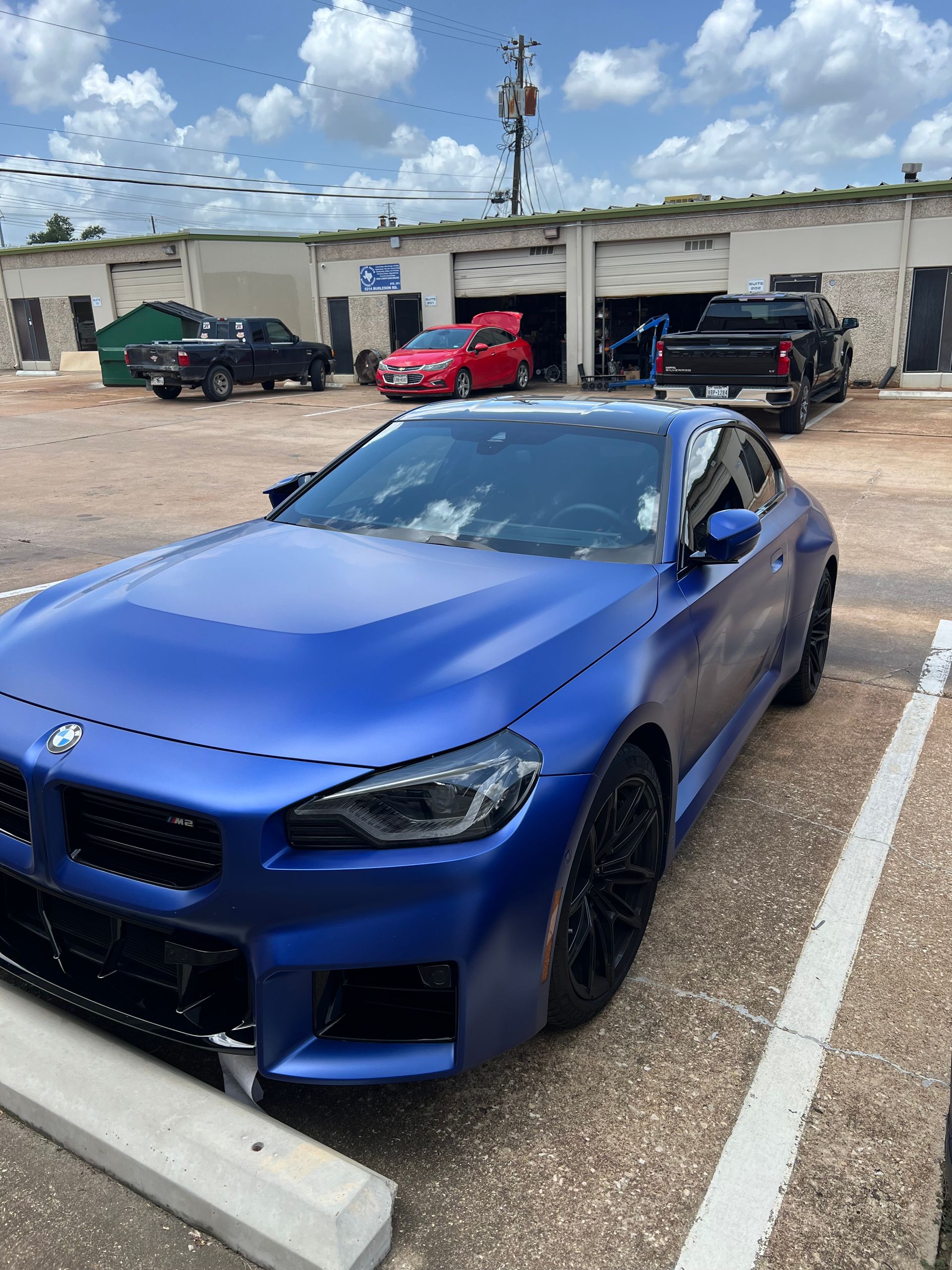 Red Porsche 911 coupe in a garage, black wheels.