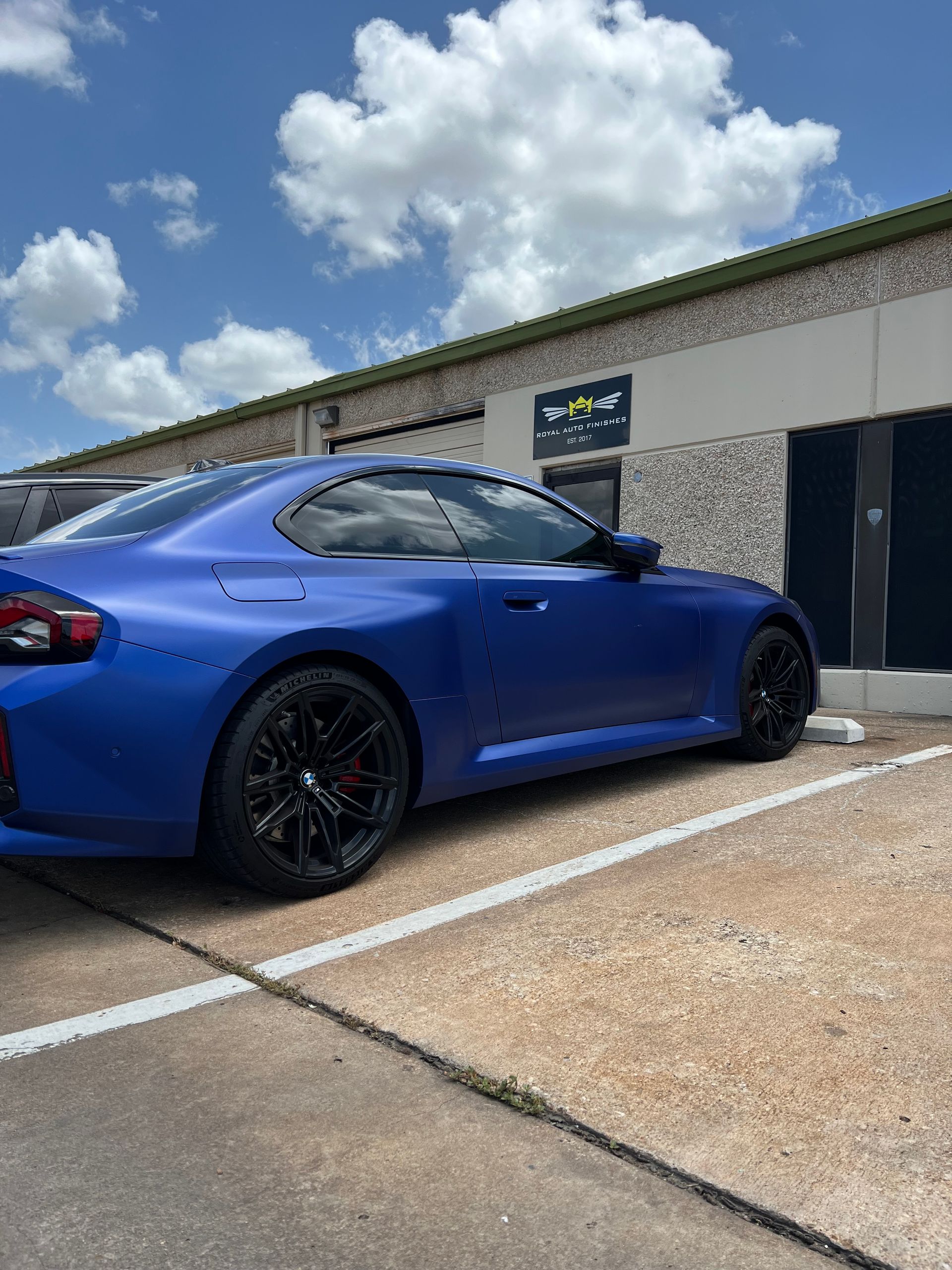 Red Porsche 911 coupe in a garage, black wheels.