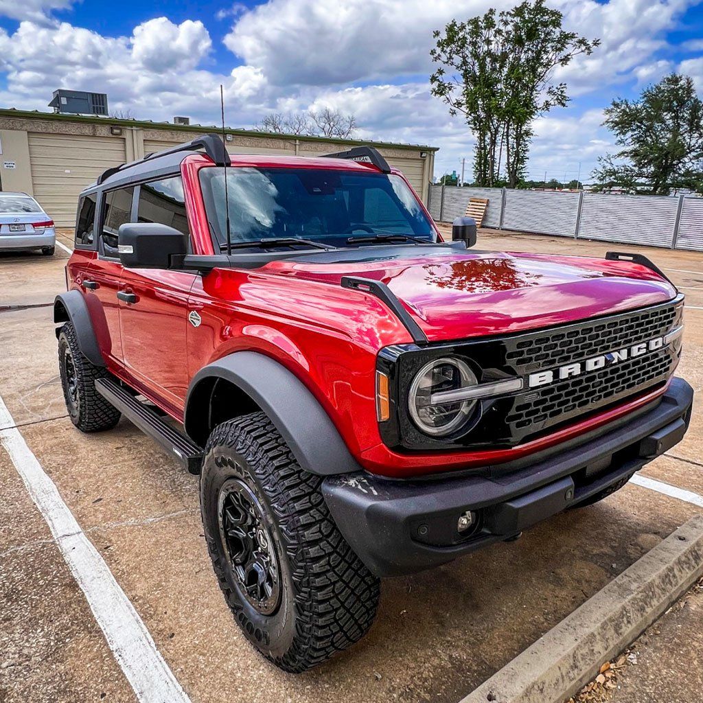 a red ford bronco is parked in a parking lot .