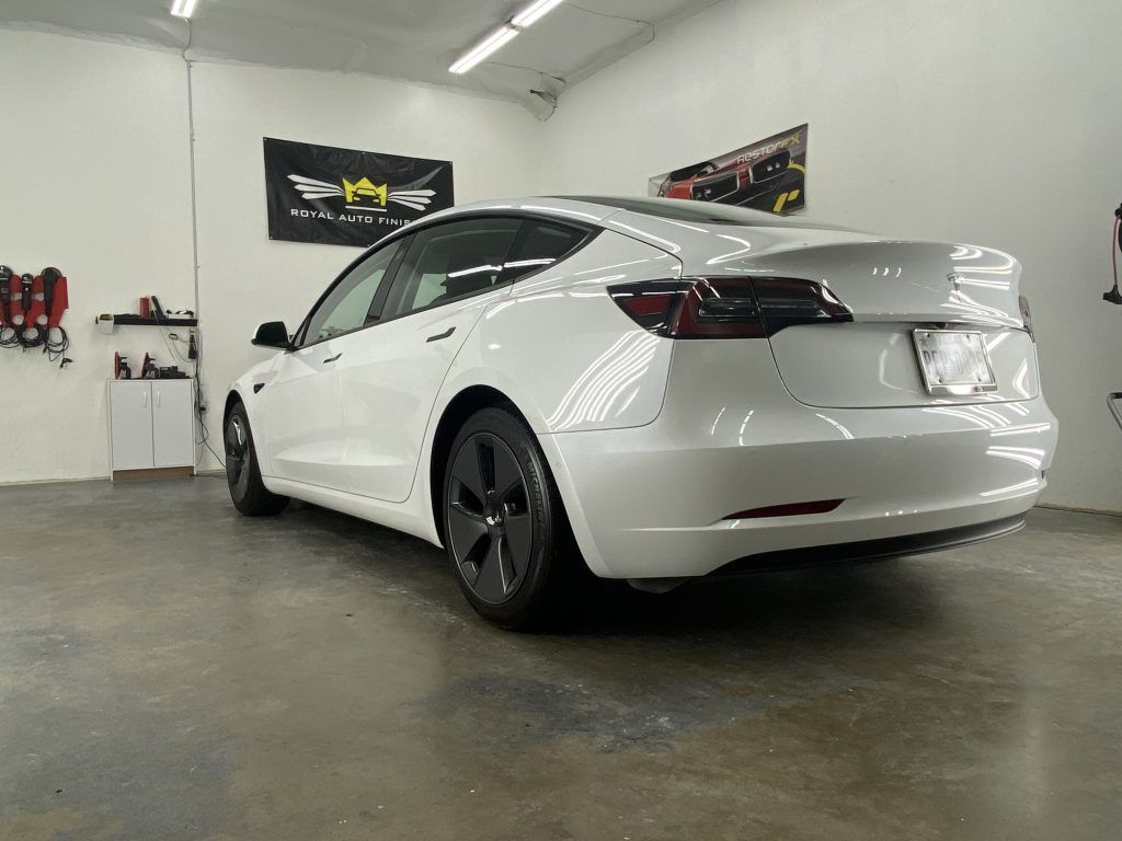a white tesla model 3 is parked in a garage .