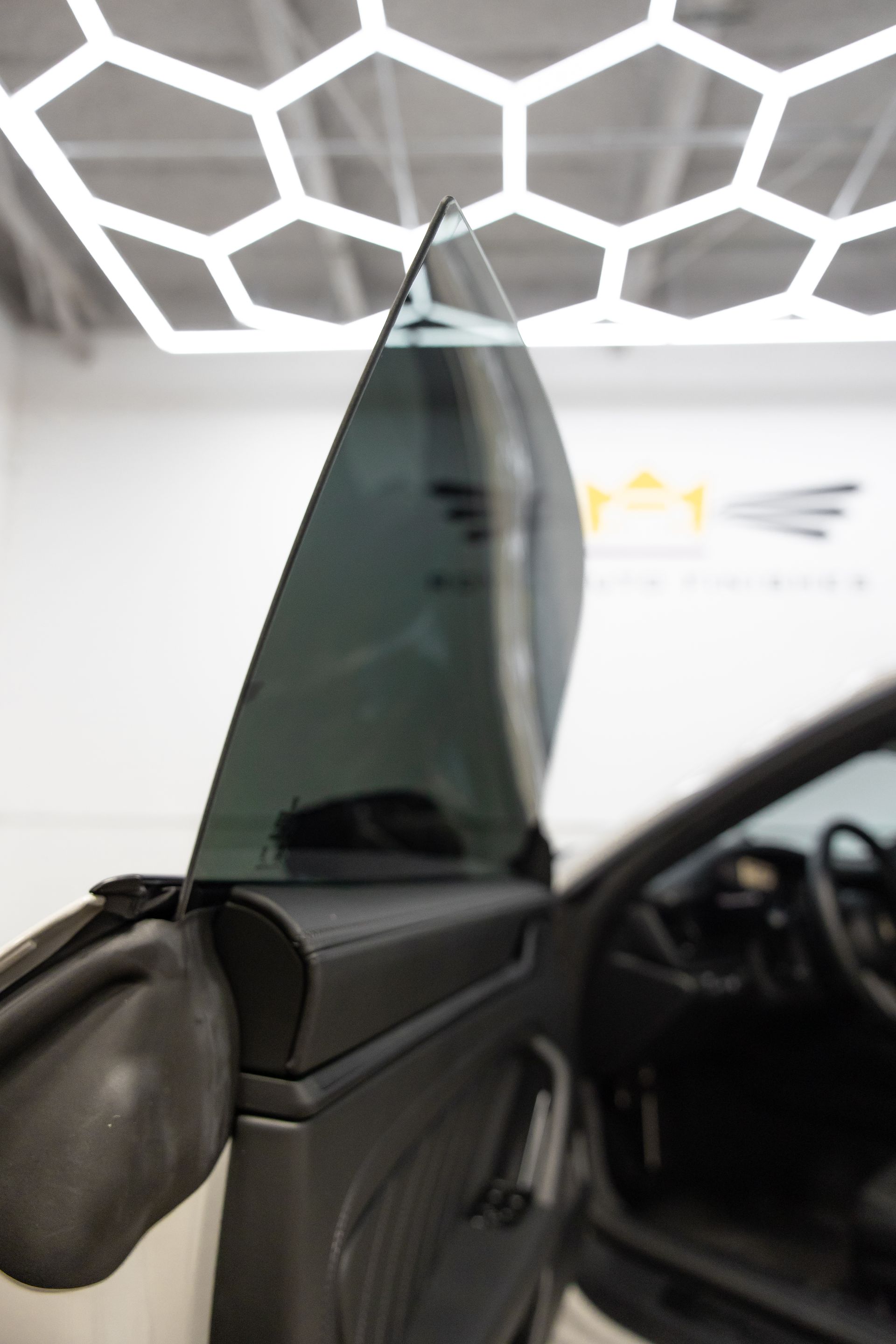 Car door with tinted window partially open, showing interior and hexagonal lights.