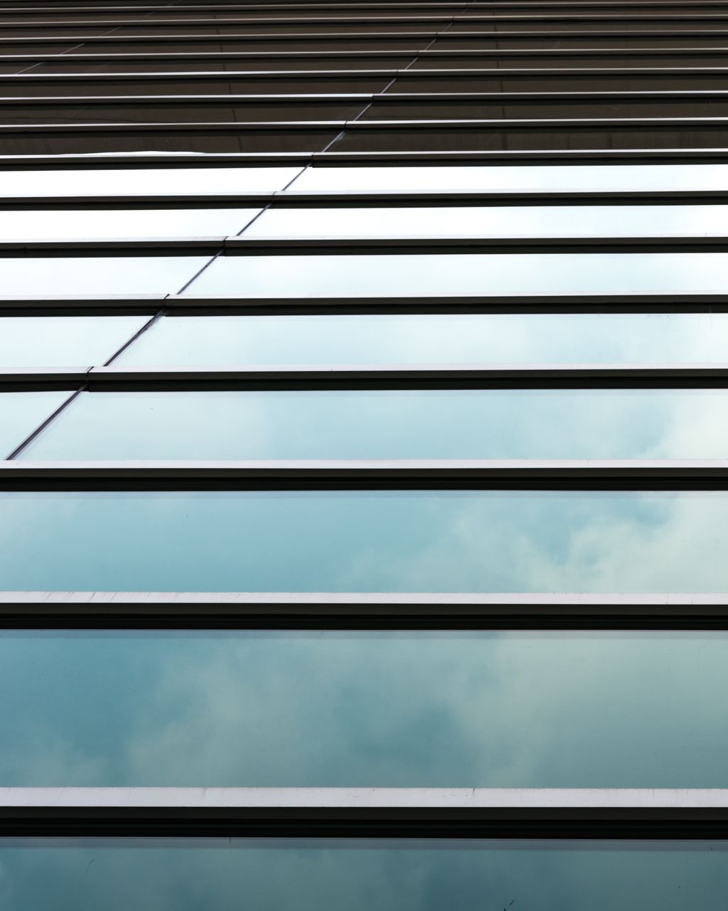 Sunlit sheer curtains frame a window overlooking a green yard. A bed with yellow sheets is in the foreground.