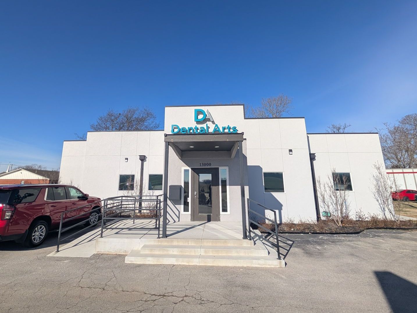 A white building with a blue sign that says da dental arts