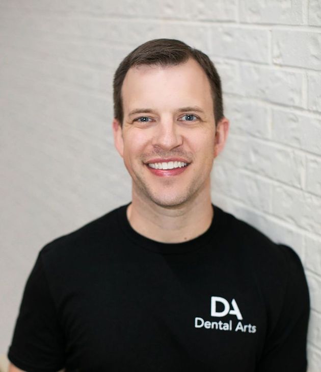 A man wearing a black shirt that says da dental arts