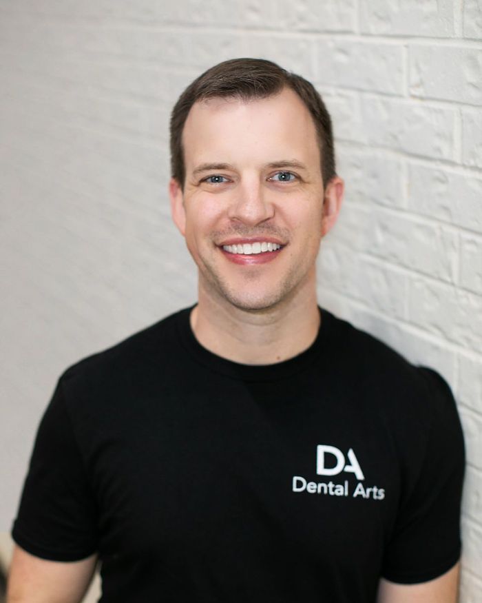 A man wearing a black shirt that says da dental arts