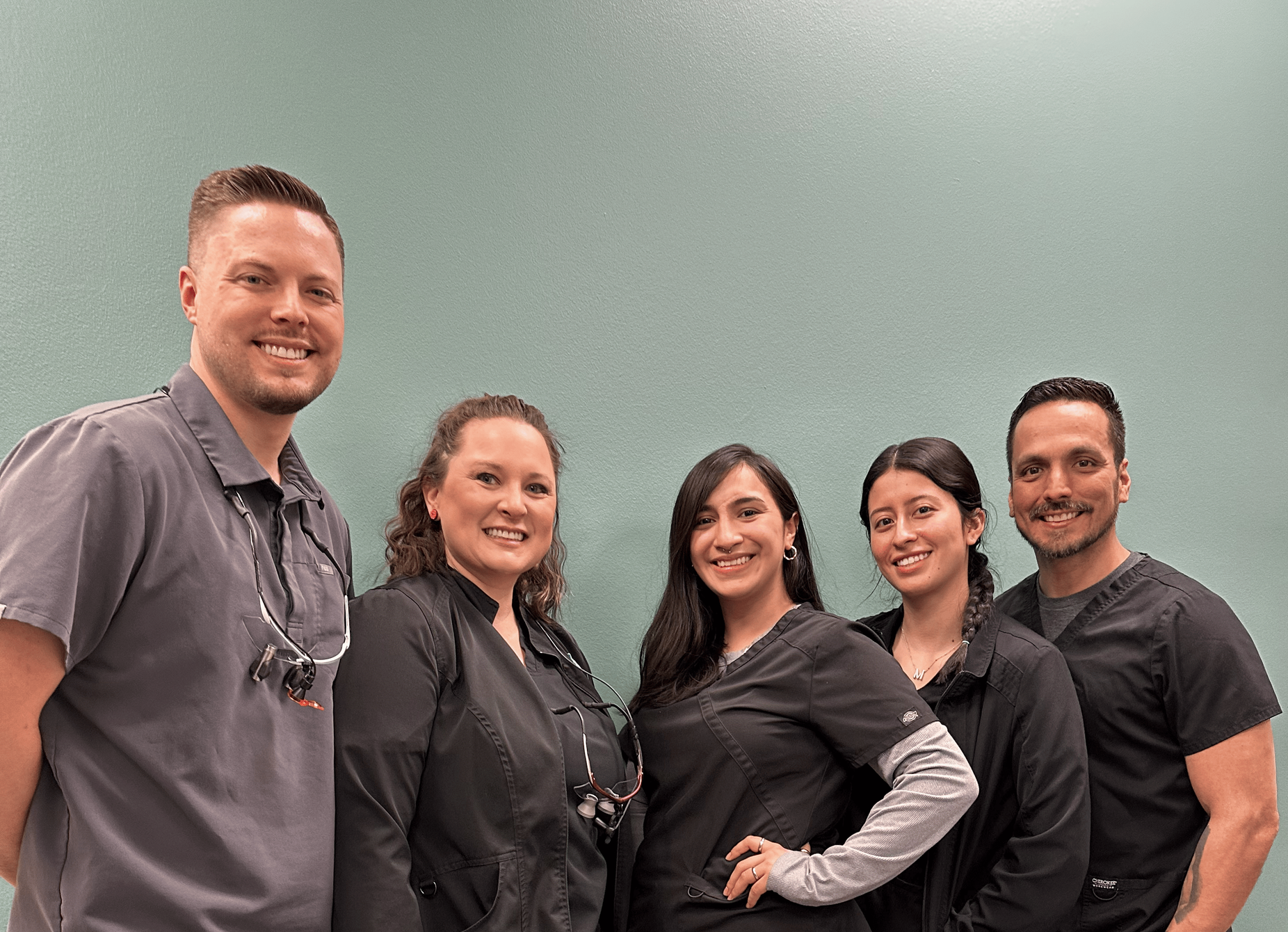 A group of people standing next to each other in front of a white brick wall.
