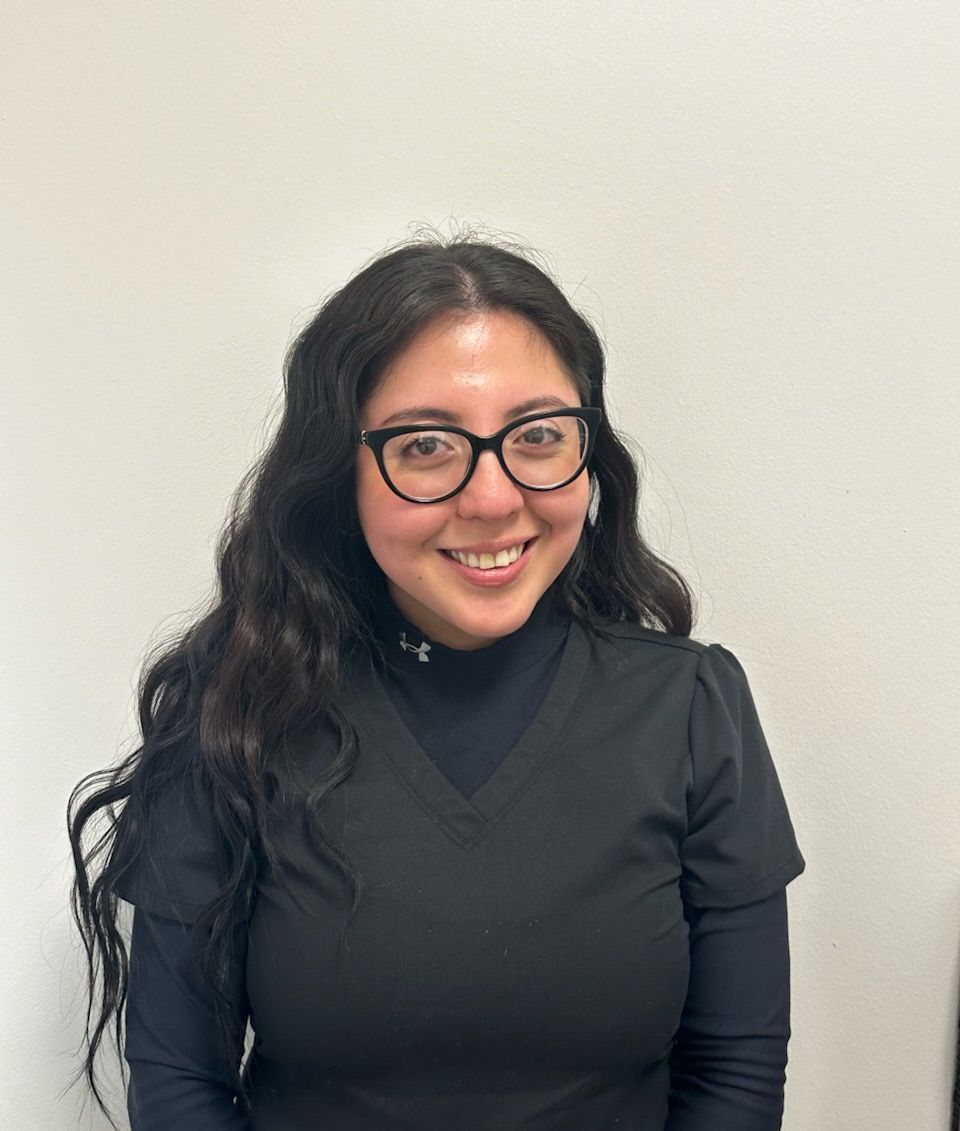 A woman wearing glasses and a black shirt is smiling for the camera.