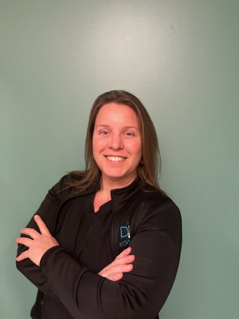 A woman in a black jacket is posing for a picture with her arms crossed.