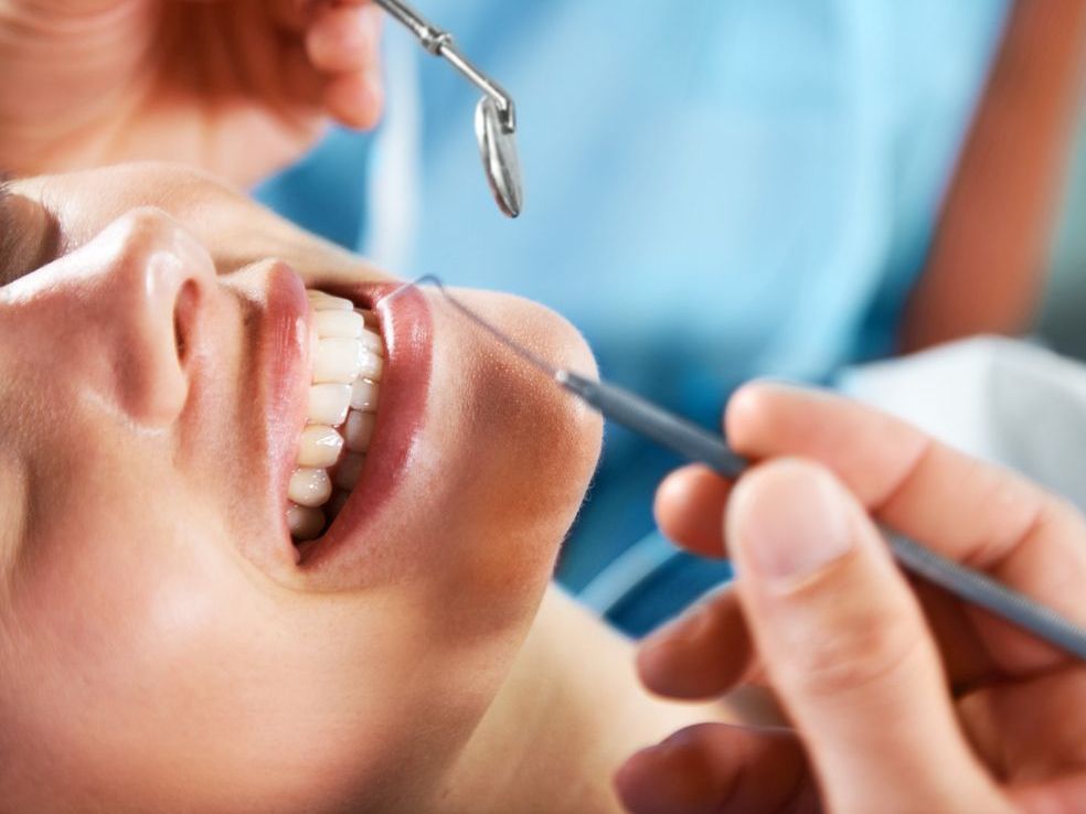 A woman is getting her teeth examined by a dentist.