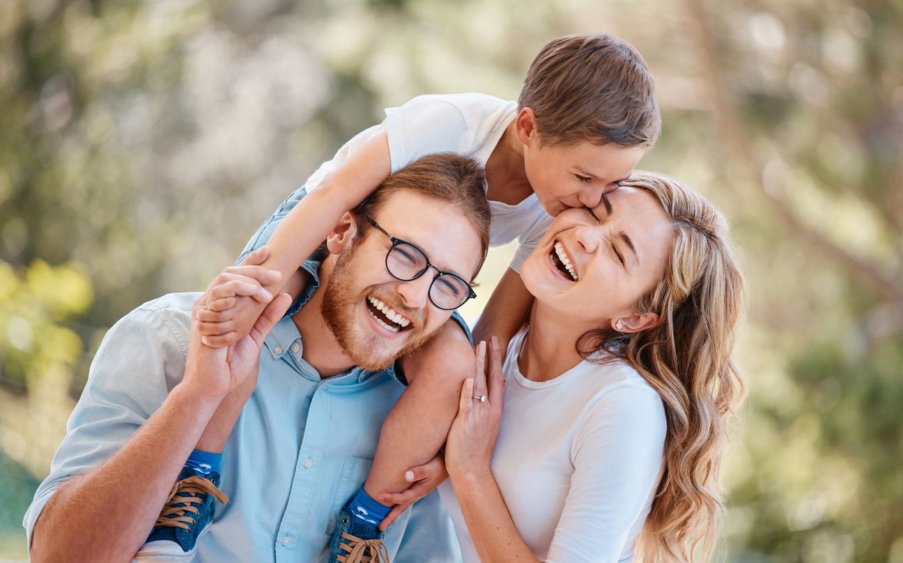A man and a woman are holding a child on their shoulders.