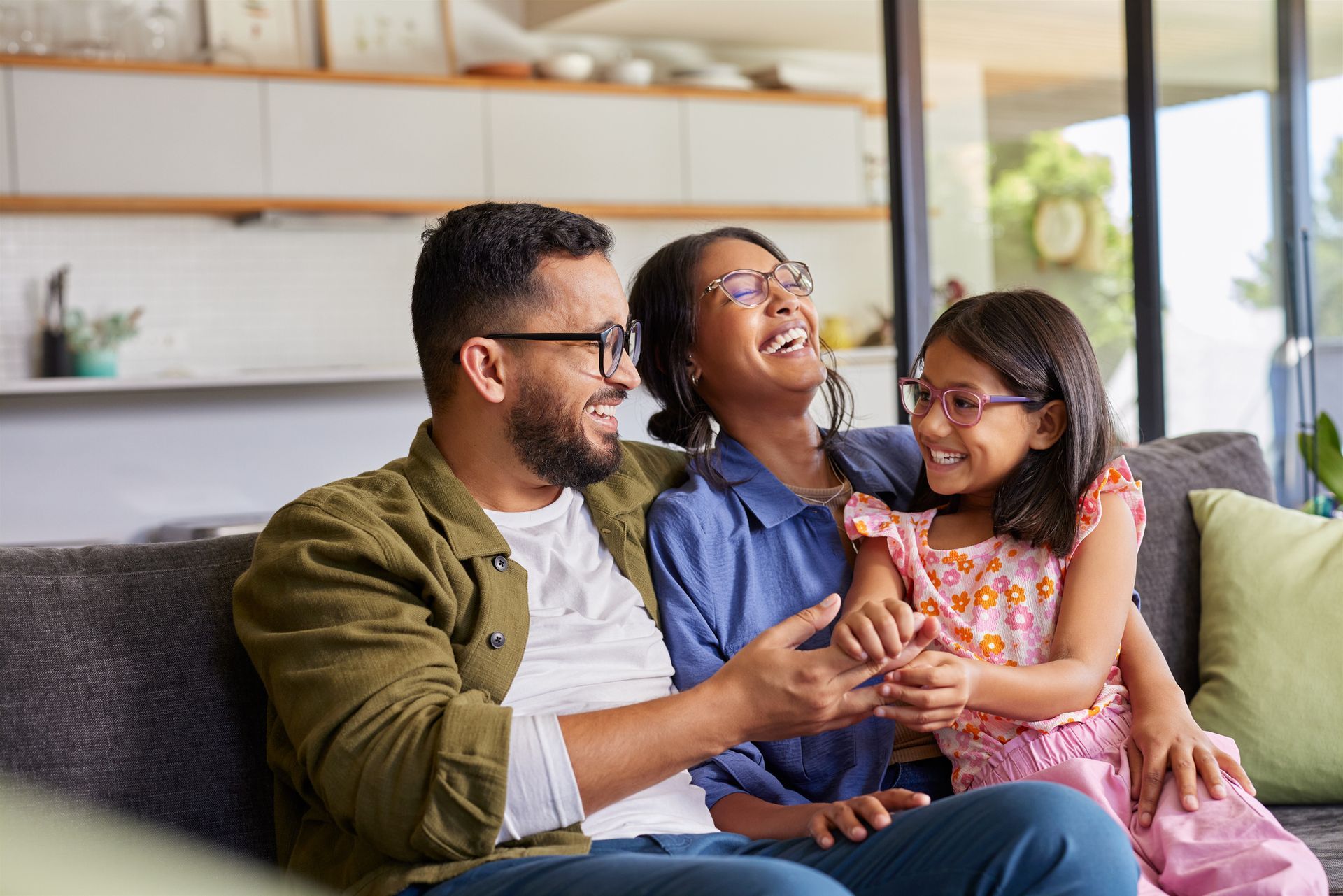 A man and woman are sitting on a couch with a little girl.