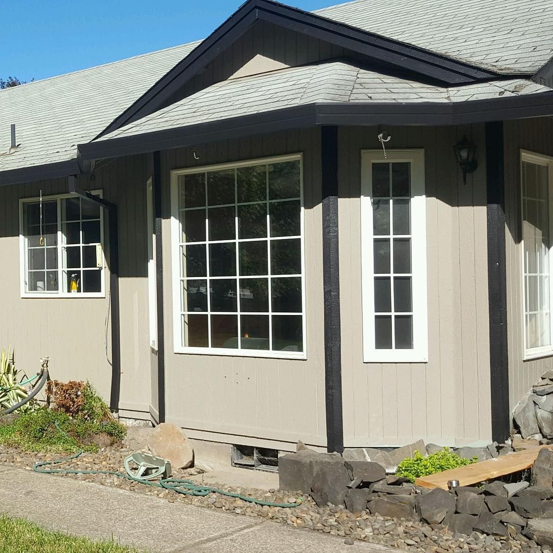 Beige house with white-framed windows, dark trim, and a gray roof.