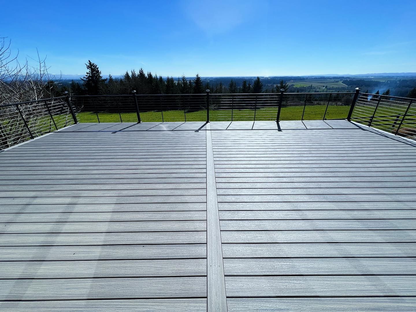 Wooden viewing platform overlooking a green landscape under a blue sky.
