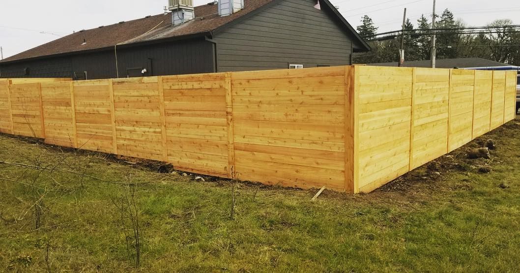 Wooden fence surrounding a building on grassy ground.