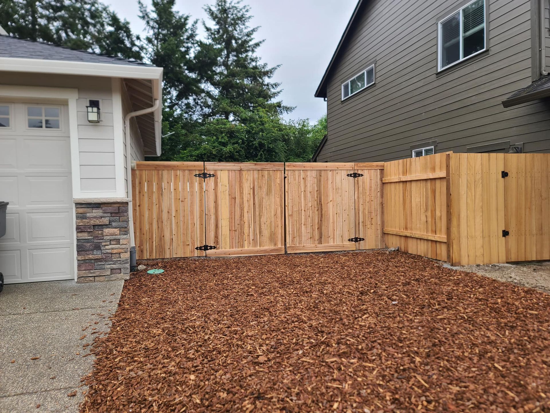 Wooden fence encloses a gravel area with wood chips. 