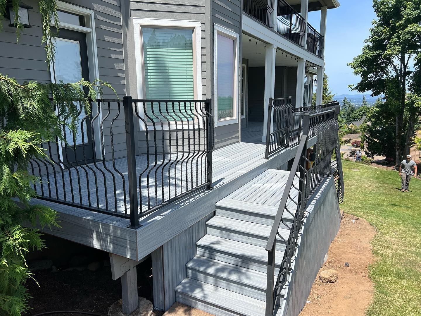 Exterior of a two-story gray house with a deck and black railings.