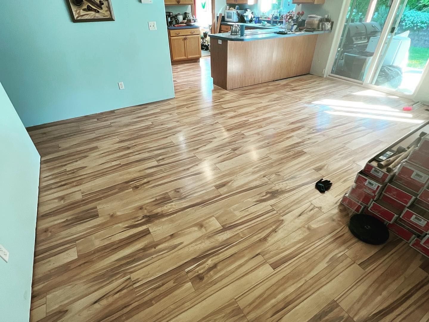 Light brown wood-look flooring installed in a kitchen and adjoining room.