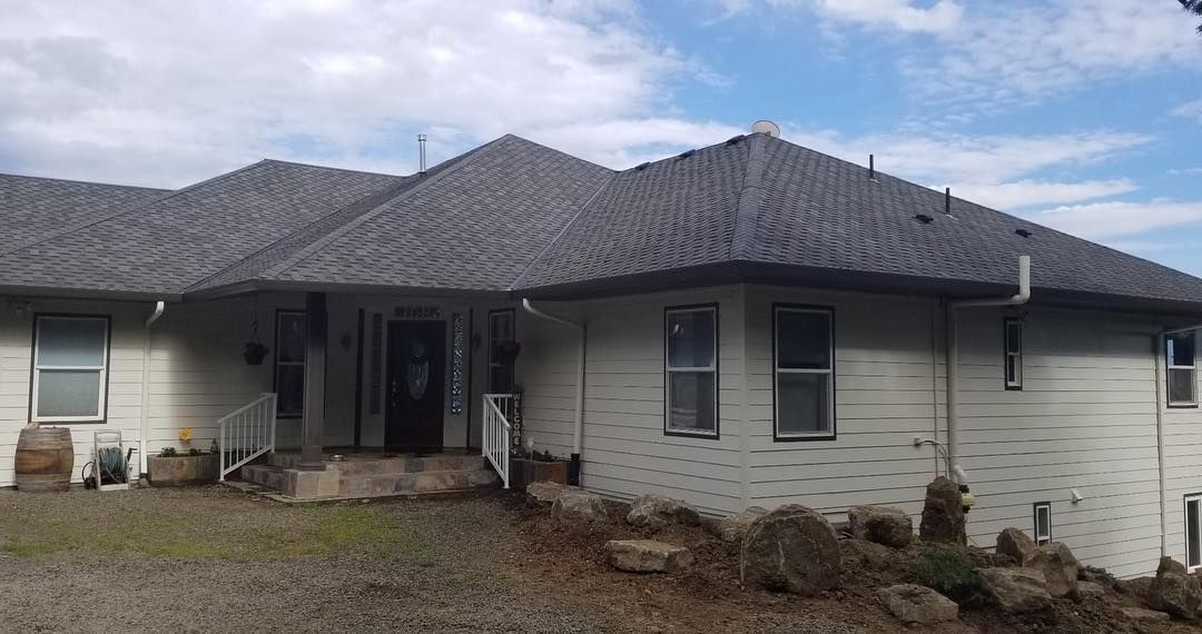 White house with dark gray roof, steps leading to the front door, blue sky.