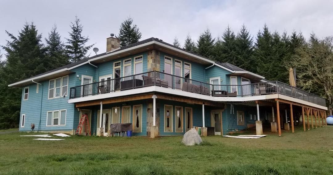 Large blue two-story house with wrap-around deck.