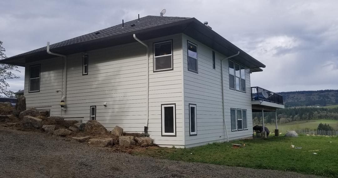 Two-story light-colored house with dark roof and trim.