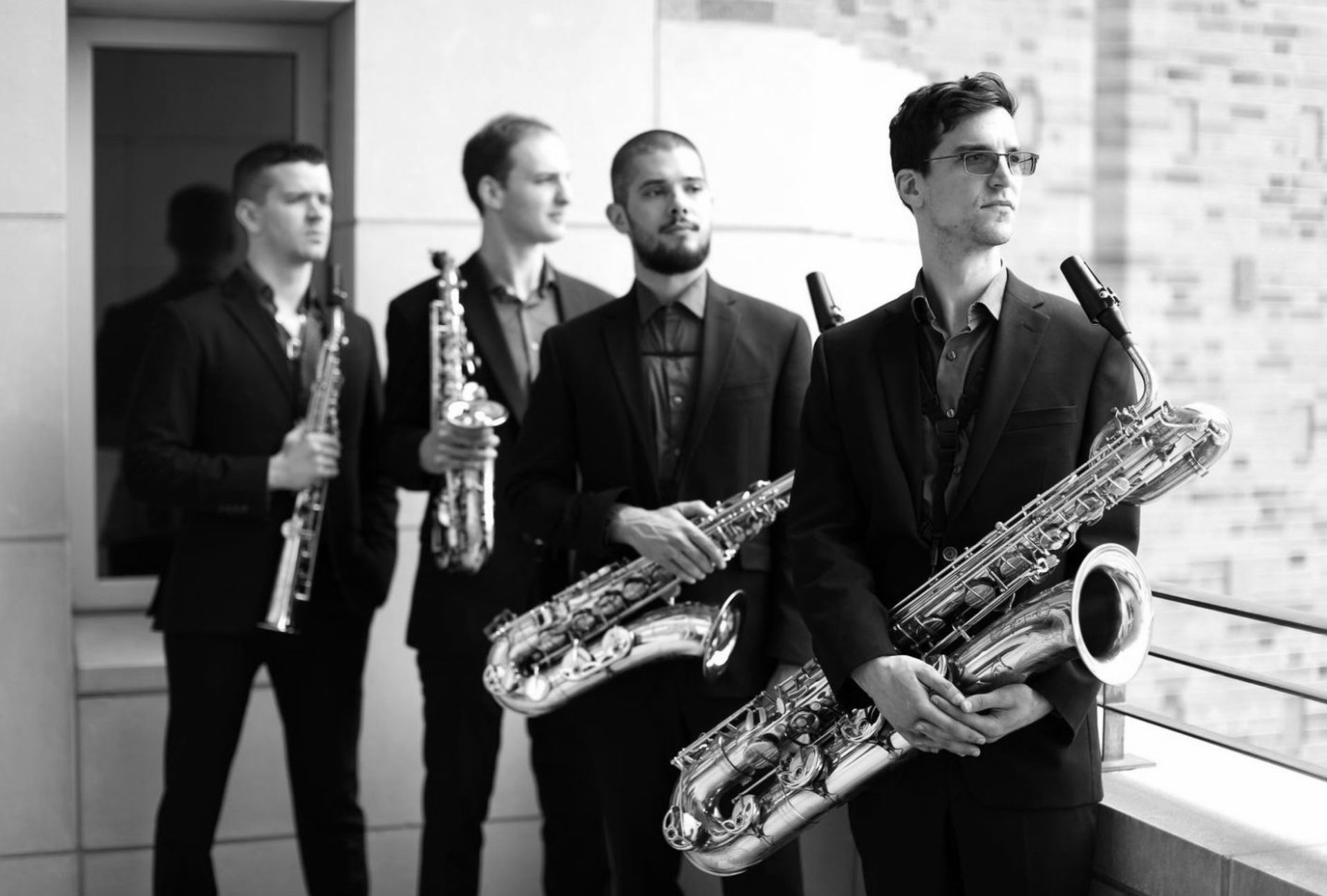 A group of men are standing next to each other holding saxophones.