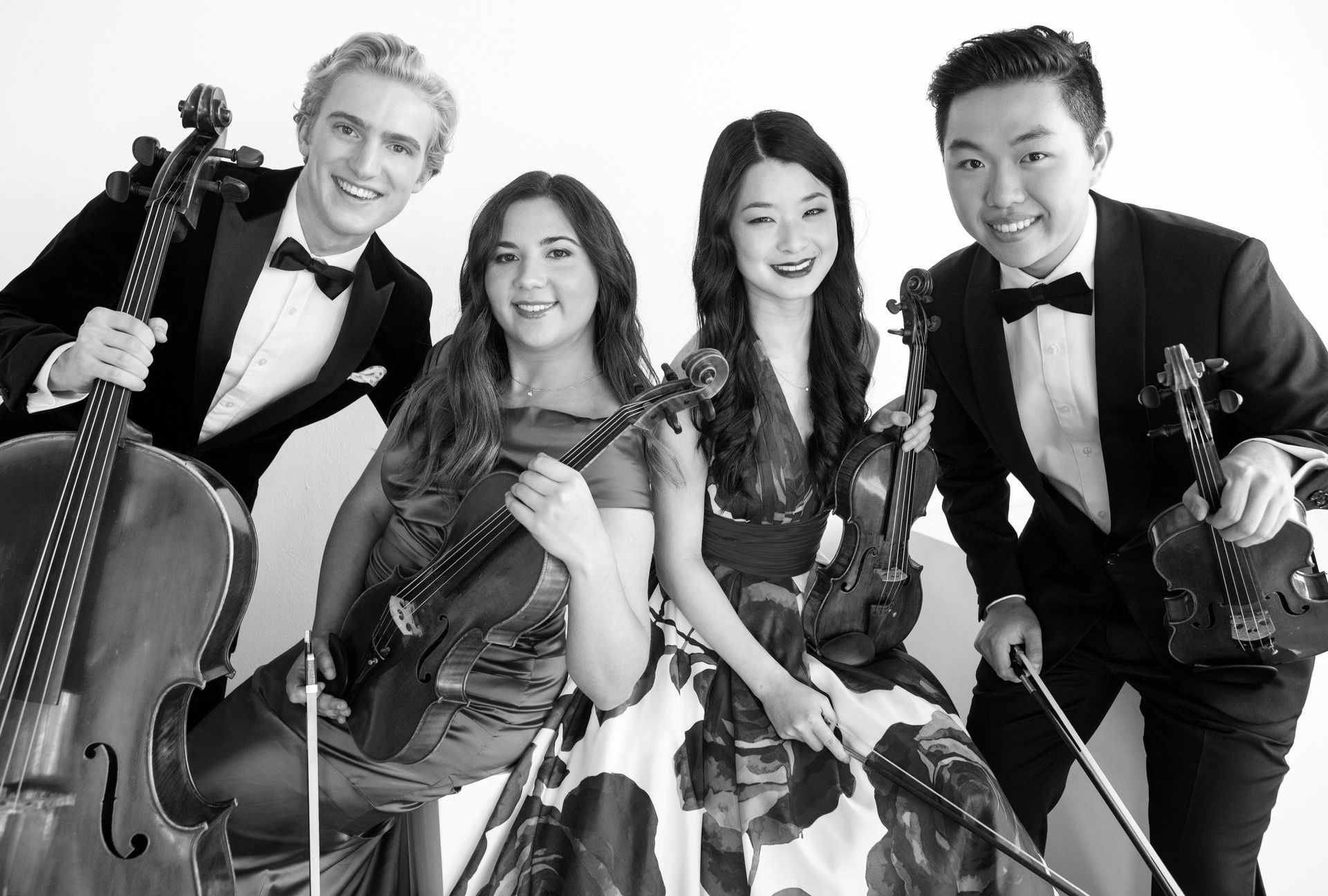 A black and white photo of a group of people playing violins and cello.