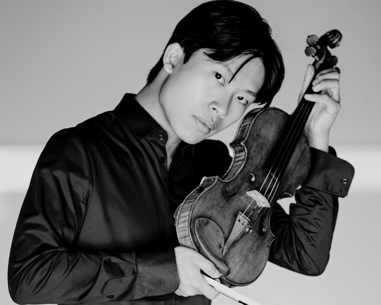 A young man in a blue shirt is holding a violin