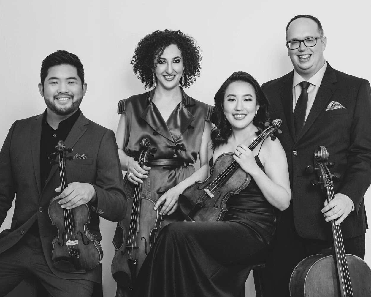 A group of people standing next to each other holding violins and cello.