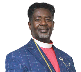 Man wearing a blue plaid suit over a red shirt with a white collar; smiling.