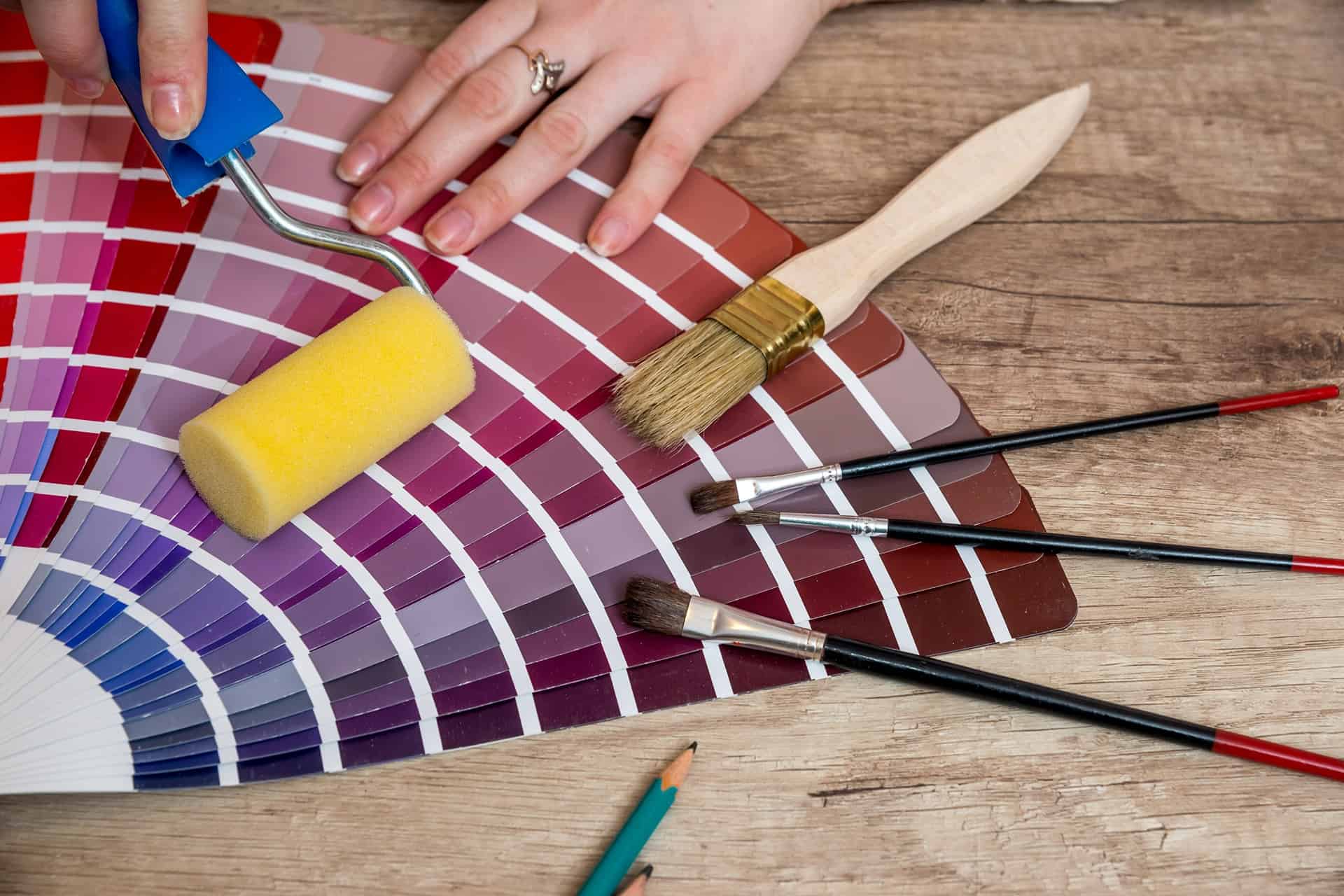 An array of paint swatches, brushes, and rollers laid out on a table