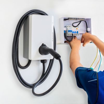 ProTech Athens | a person is installing an electric car charger on a wall.