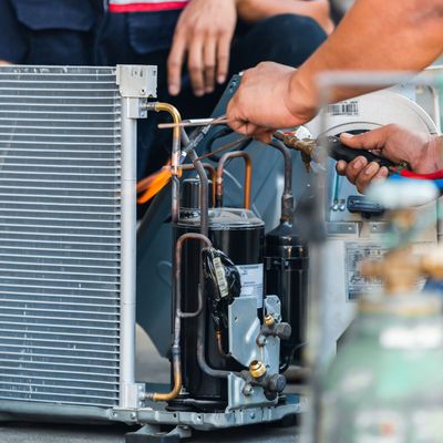 ProTech Athens | a man is working on an air conditioner with a welding torch.