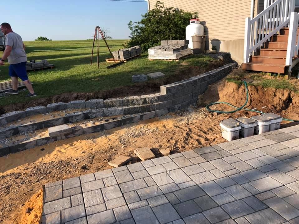 A man is working on a patio in front of a house.