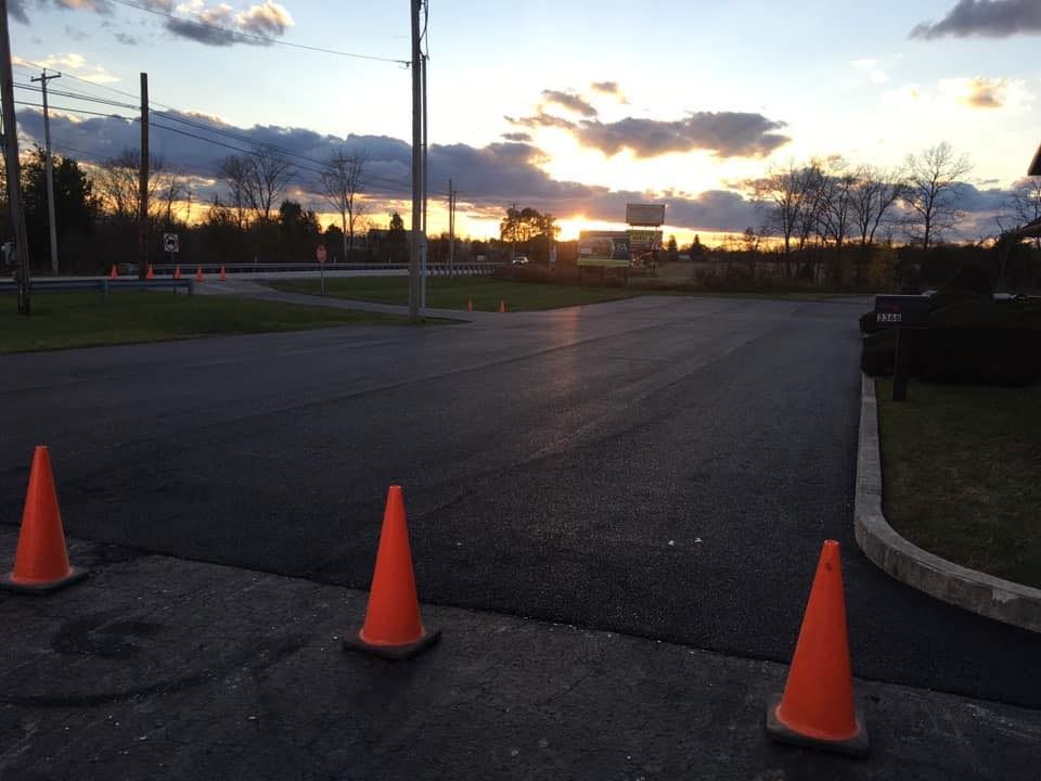 Orange traffic cones on the side of a road at sunset