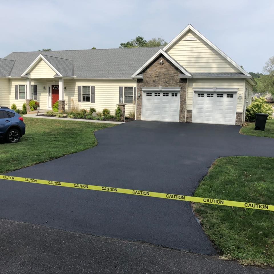 A car is parked in front of a house with a caution tape around the driveway