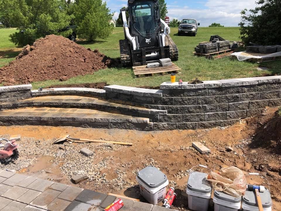 A bulldozer is working on a brick wall in a yard.